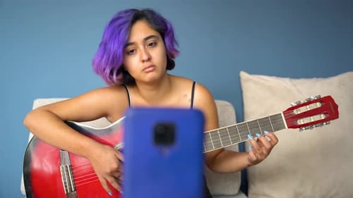 Young Adult Plays Guitar at Home for Online Lesson