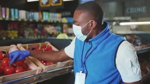 Portrait African American Sales Wear Gloves and Mask Man Puts Vegetables on the Shelf Look at Camera
