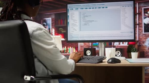 Programmer Wearing Headphones Types Code Into PC Developing Software