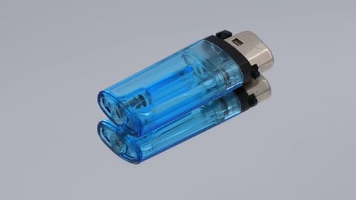 Blue plastic lighter rotating on reflective mirror surface