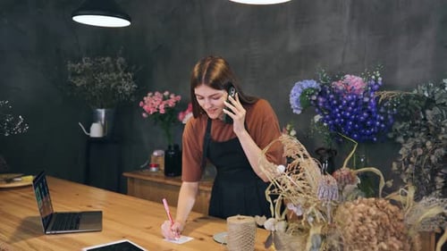 A Florist in a Flower Shop Takes an Order to Create a Bouquet From a Client Over the Phone Client