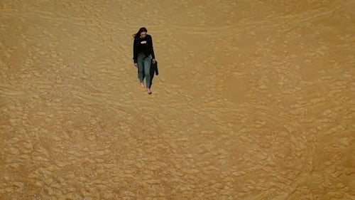 Woman Walking Barefoot on Deserted Sandy Beach Under Bright Sunlight Female Strolling Alone Across
