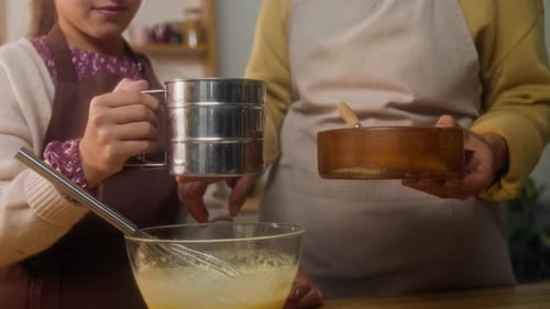 Girl Sifting Flour in Dough Cooking with Grandma in Kitchen