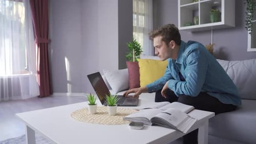 Glücklicher männlicher Student schaut auf Laptop und Bücher.