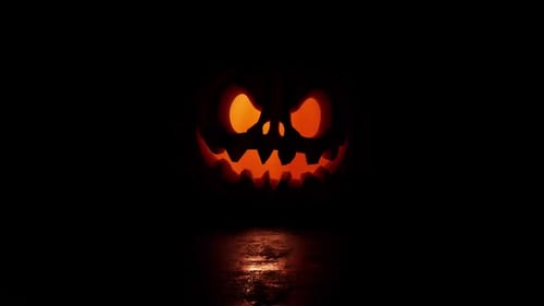 Spooky jack o'lantern glows ominously in dark, wet night