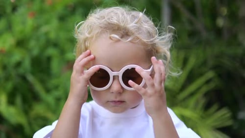 Close Up Portrait of Little Girl of Angelic Appearance in Bushes Trees Park Caucasian Blonde