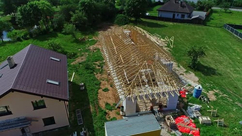 Rotating aerial view of the construction of a roof with wooden beams in the countryside