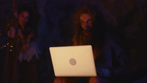 A Mysterious Figure Sitting in an Isolated Dark Cave While Using a Laptop for Work