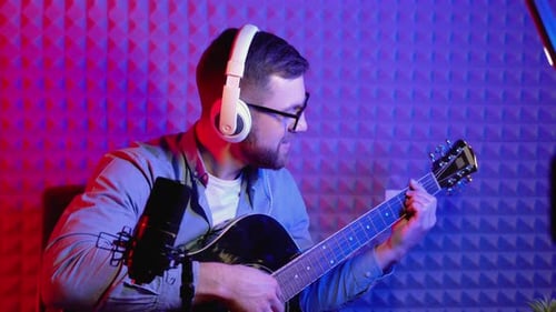 Young Man Playing Guitar and Singing in Studio