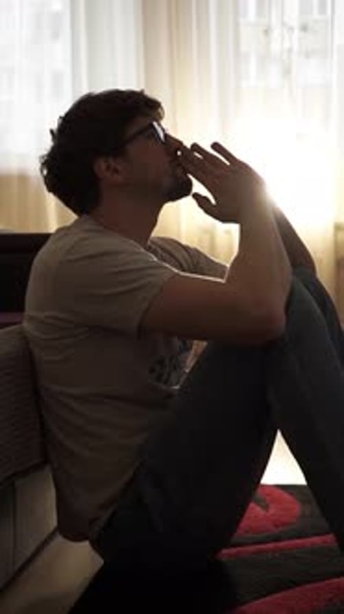 Man Sits on Floor with Hands on Face