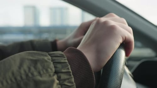 Close Up Tapping Steering Wheel to Music with Blur City Skyline Background