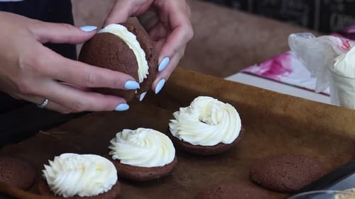 Woman Assembling Iced Cookie Sandwich at Home