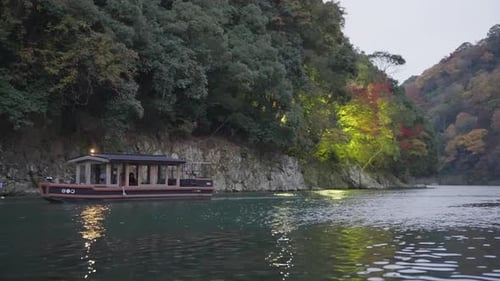 Boot fährt im Spätherbst in Japan bei Arashiyama den Katsura River hinauf