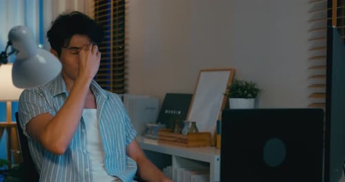 Tired Young Adult Working on Laptop at Night