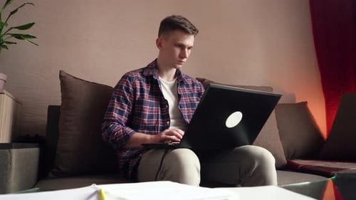 Man Working on Laptop on Couch at Home