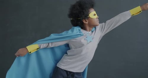 Slow Motion of Adorable African American Child Wearing Mask and Cape Standing in Super Hero Position
