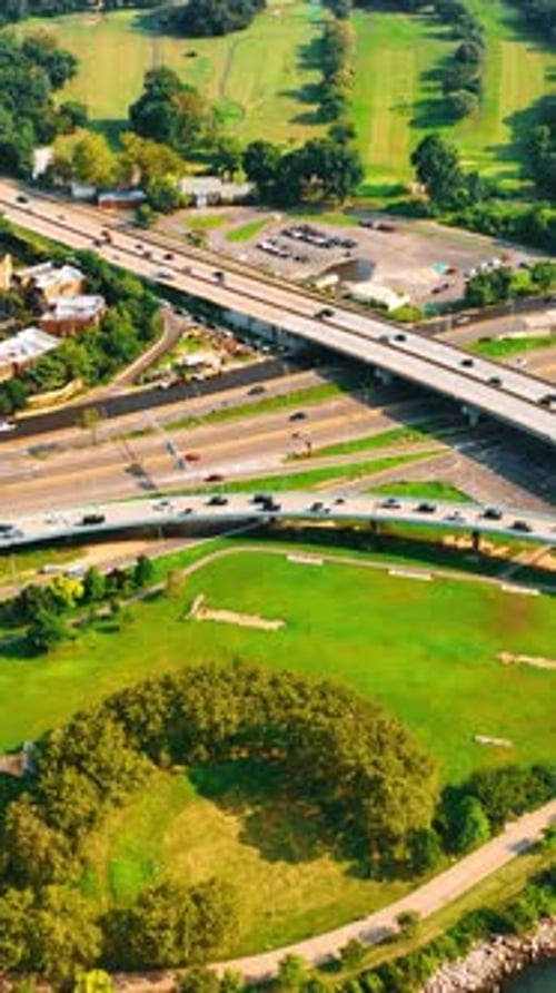 Roads and freeways intertwine on the exit from the bridge. Daytime traffic in the big city. Top view