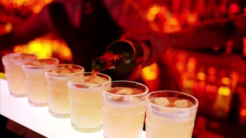 Barman making cocktails with whiskey liquor alcohol at the bar at night with red neon lights, slow m