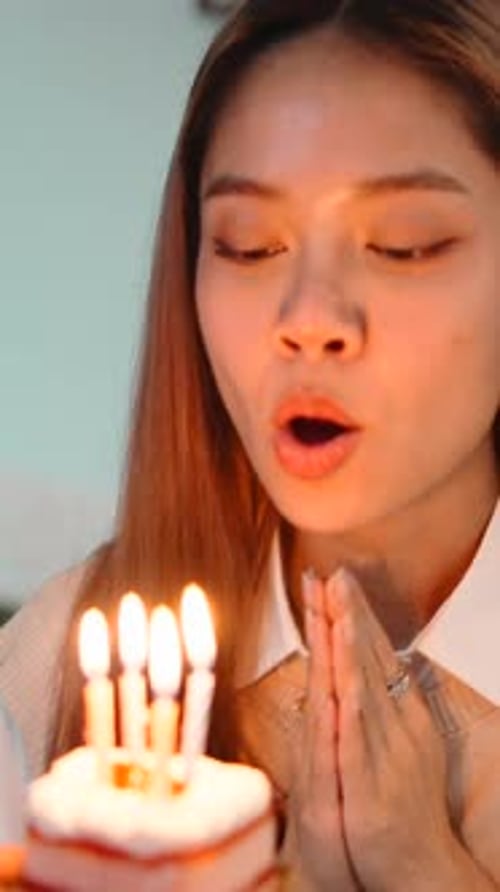 Smiling Woman Blows Out Birthday Candles on Cake