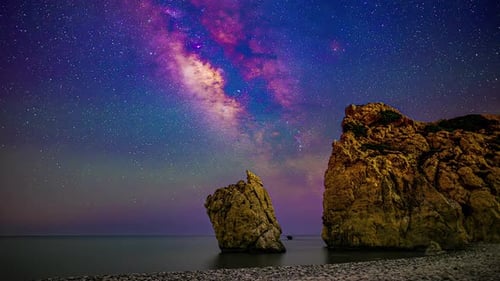 Timelapse view of colorful night sky stars milky way with huge rocks in foreground.