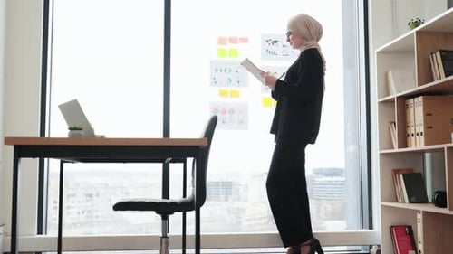 Woman Reviews Data on Tablet in Modern Office