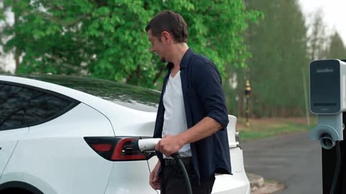 Man recharging battery for electric car during road trip. Exalt