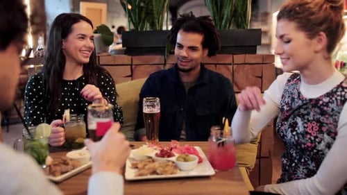 Friends Talking and Eating Appetizers at Bar