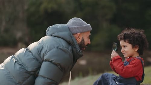 Père et fils joyeux explorant la nature avec une loupe