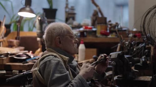 Senior Elderly Master Jeweler in Wheelchair Works in a Workshop