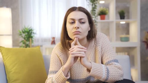 Young Woman Thinking Deeply on Couch in Bright Room