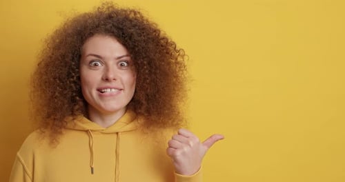 Surprised woman pointing to the right with thumb