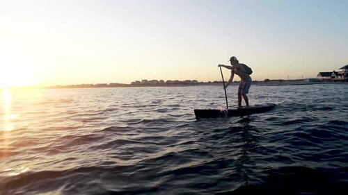 Man Paddle Boarding at Sunset on the Ocean