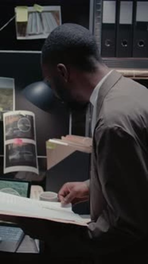 Man Examines Files in Dark Police Office