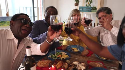selfie of group of friends toasting with wine glasses on the table while having dinner and celebrati