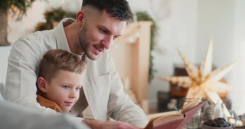 Man and Boy Reading a Book Indoors