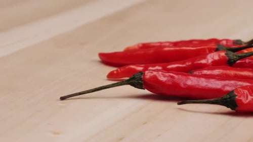 Ein rotes Chili-Pfeffer-Gemüse, das auf einem Holztisch liegt, Nahaufnahme Die Paprika erscheint frisch und reif