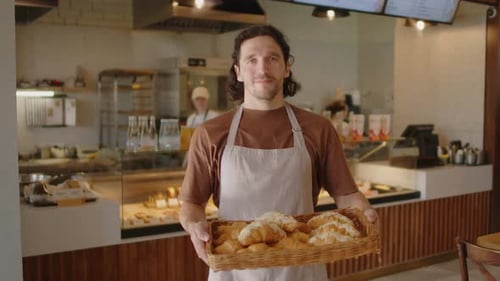 Baker Holding Basket of Croissants in Bakery