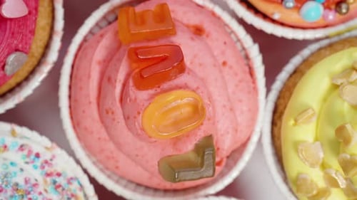 Top view of colorful and unique cupcakes with the word "Love" written and heart-shaped sprinkles, ro