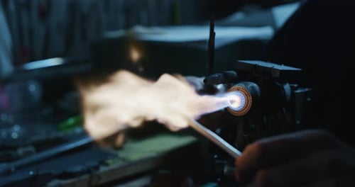Zeitlupenmakro eines Glasbläsers, der mit Flammen auf einem handgefertigten Kunststück aus Glas von preciou arbeitet