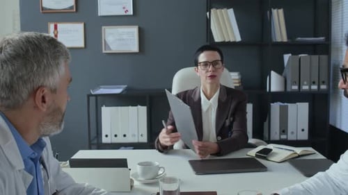 Female Clinical Manager Leading Team Meeting with Doctors in Medical Office