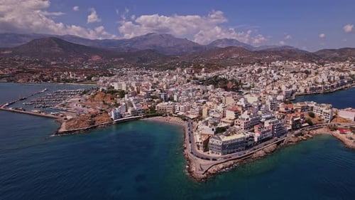 Aerial view of a coastal town in Crete with mountains in the backdrop
