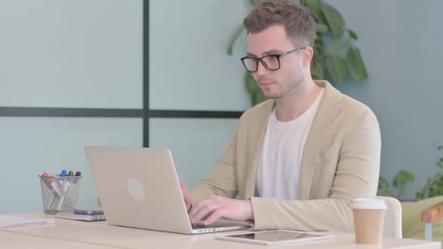 Young Businessman Leaving Office after Closing Laptop
