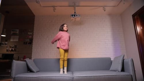 Girl Jumping on Sofa in Living Room