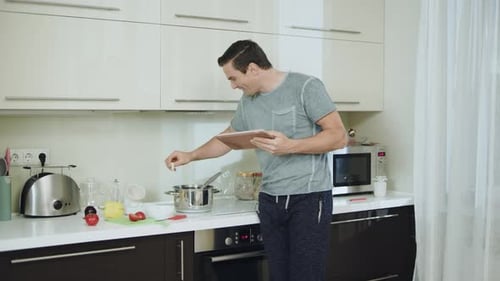 Man Follows Recipe on Tablet While Cooking