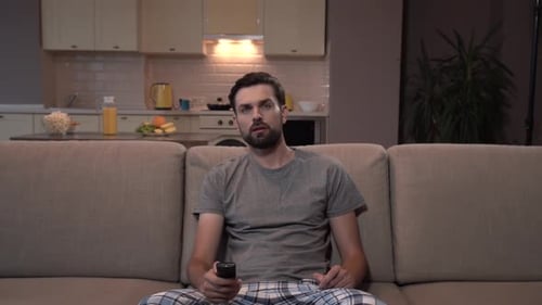 Man Laughing While Sitting on Couch with Remote