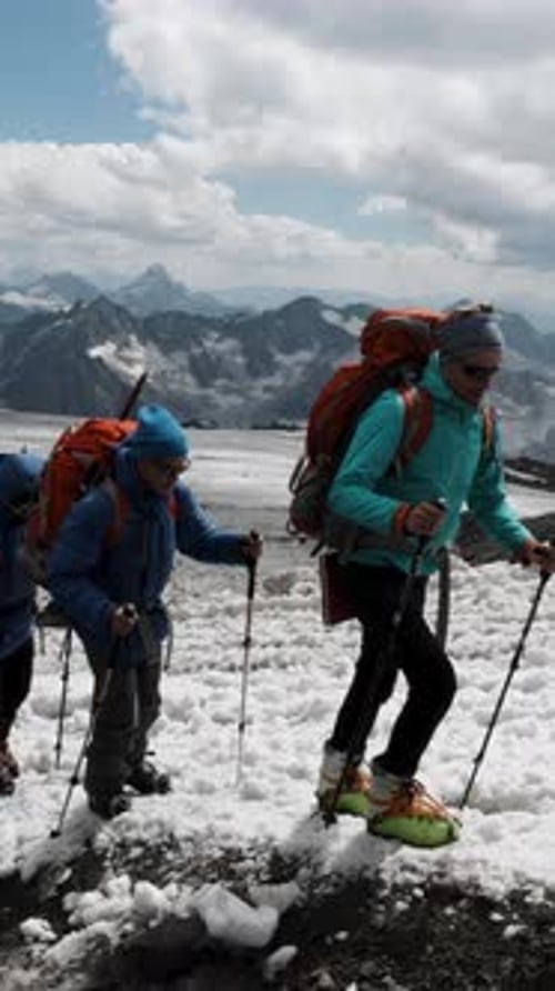 Young Climbers in Warm Jacket Helmets and Special Glasses Moving Up on a Mountain Slope One By One