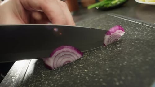 Hands Slicing a Red Onion in Kitchen