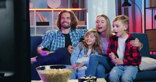 Smiling Family Watching Television at Home Together