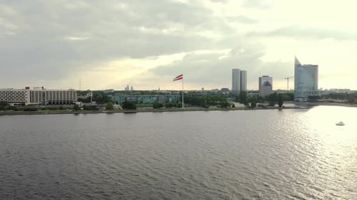 Beautiful view of Riga on the shore of Daugava River, flag of Latvia, 4k