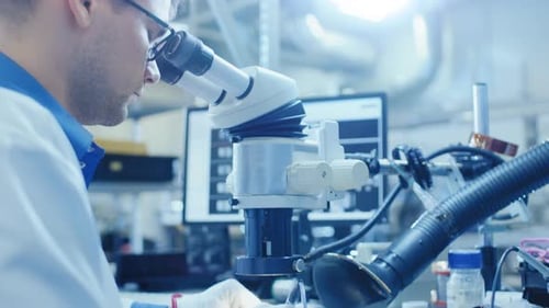 Close Up of an Electronics Factory Worker in White Work Coat Soldering a Printed Circuit Board Thro